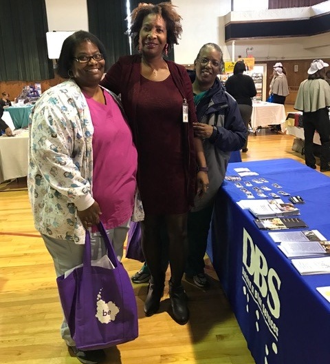 La’Verne Scott standing next to two women at the DBS exhibit table